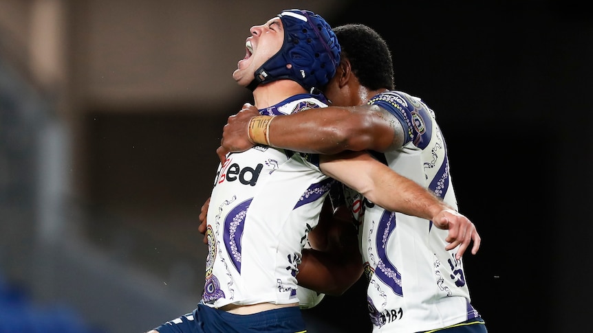 Two Melbourne Storm NRL players celebrate a try against Newcastle.