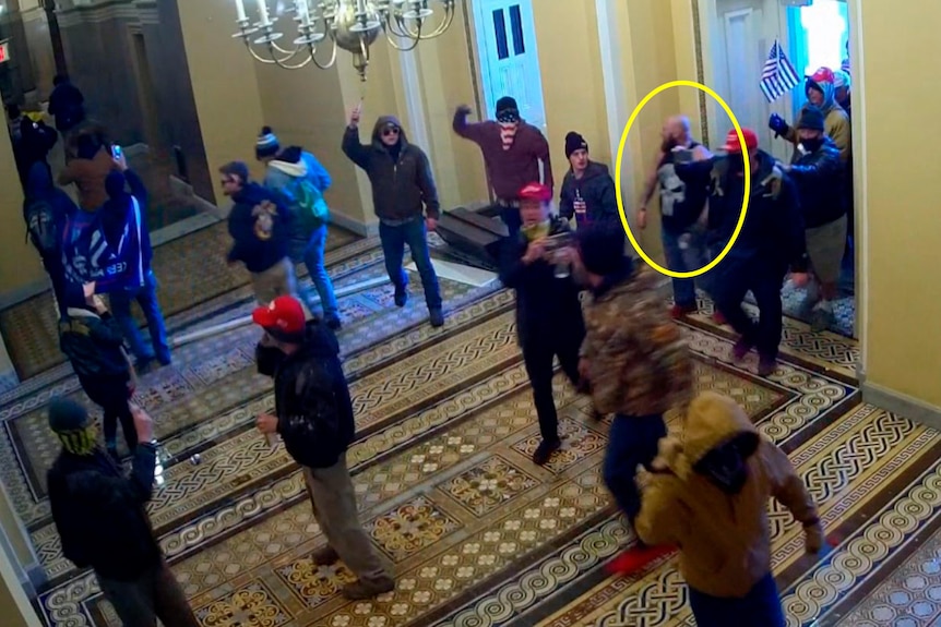 A yellow circle identifies a man in a crowd entering a building. 