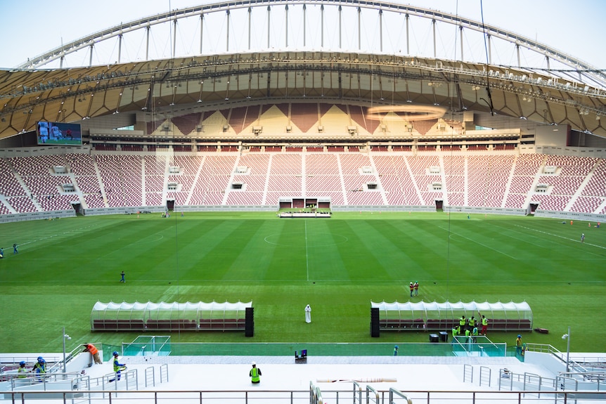 An inside view of a football stadium with workers present but no crowd.