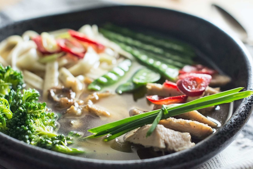 A bowl of chicken soup with vegetables.