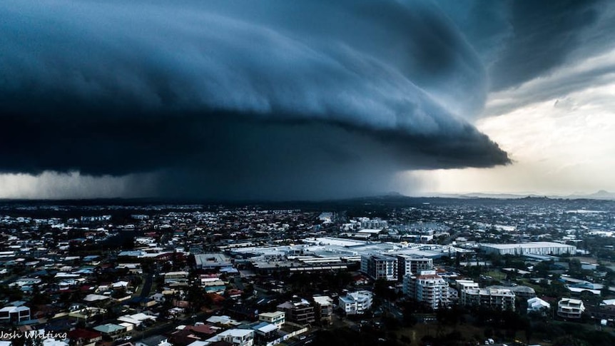 A very dark and large cloud hangs over a town