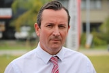 WA Labor Leader Mark McGowan looks down the barrel of the camera wearing a white business shirt and a red tie.