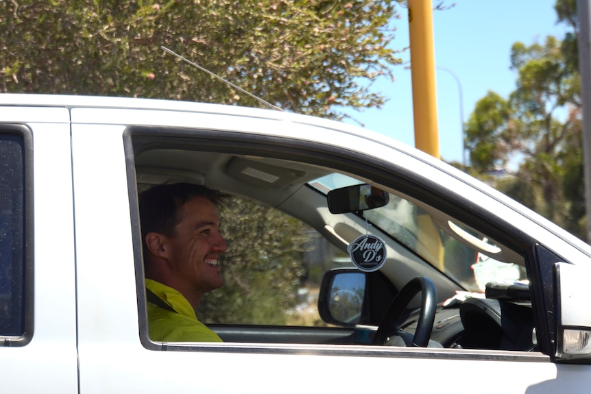 A man in high-vis in the front seat of a white ute.