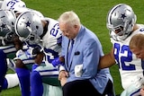Dallas Cowboys NFL players and owner kneel during the national anthem.