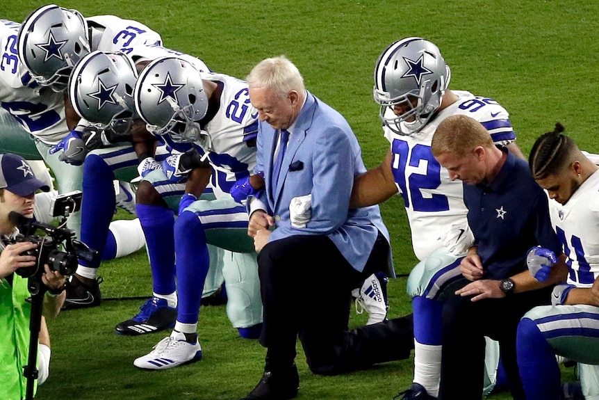 Dallas Cowboys NFL players and owner kneel during the national anthem.