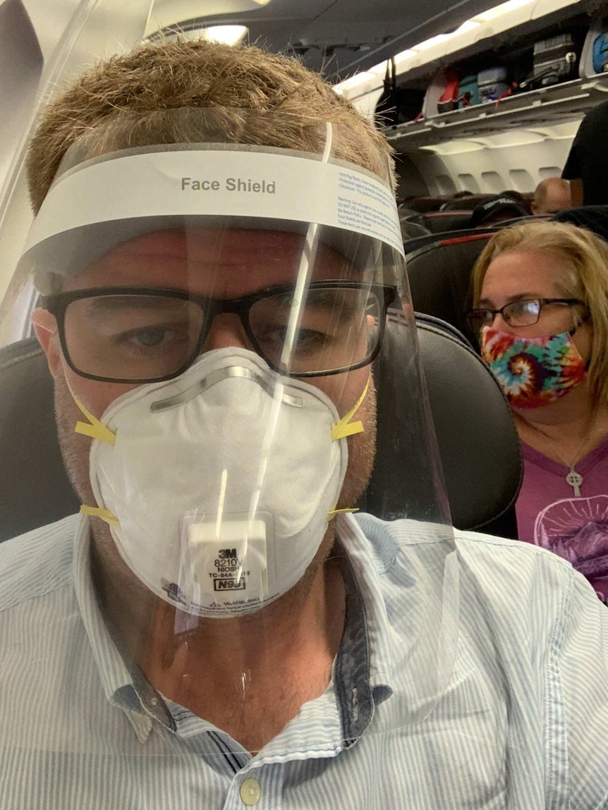 Lipson on plane wearing face mask and shield.