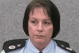 A woman in police uniform sits down next to a microphone.