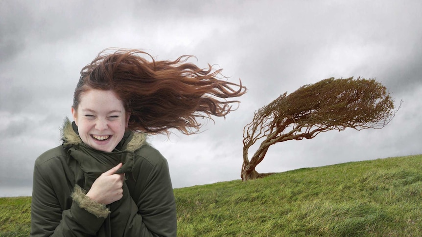 A woman standing on a hill in windy weather