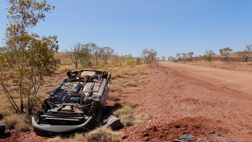 An overturned car sits by the side of the Tanami Road.