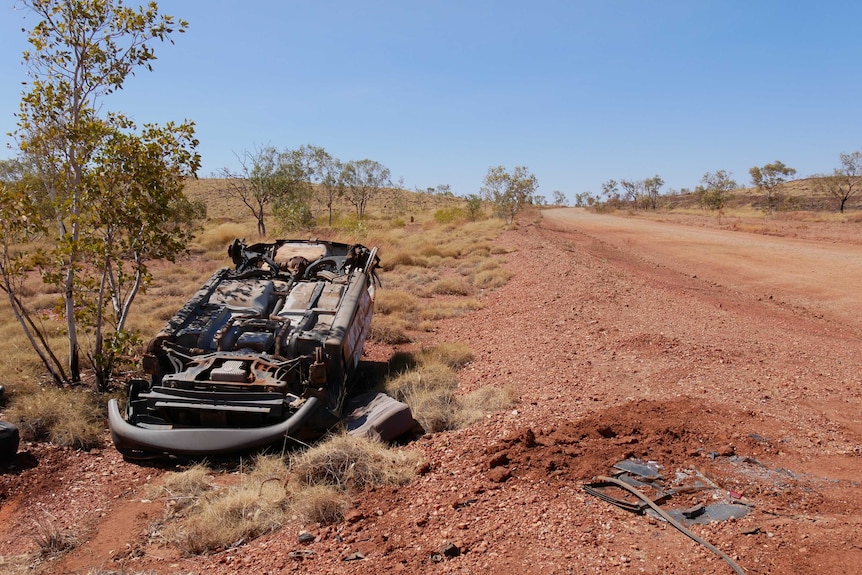 An overturned car sits by the side of the Tanami Road.
