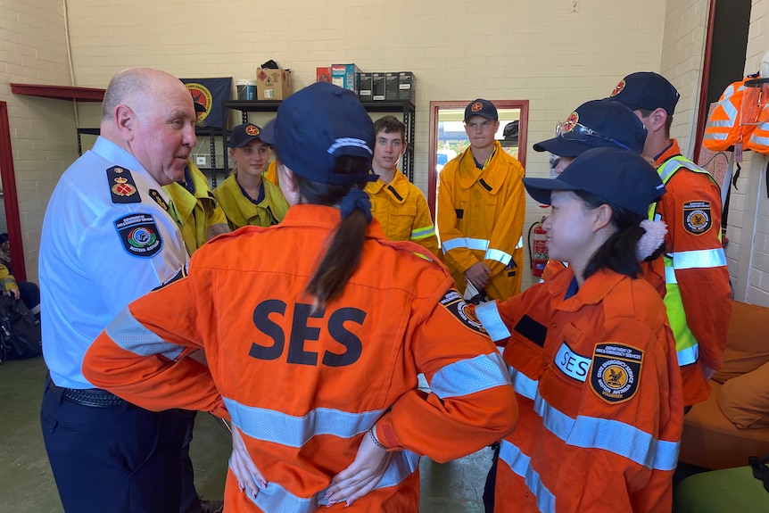 A man in a DFES uniform talks to volunteers in SES uniforms