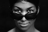 A young Aretha Franklin wearing sunglasses that are sitting on her nose, but with eyes visible