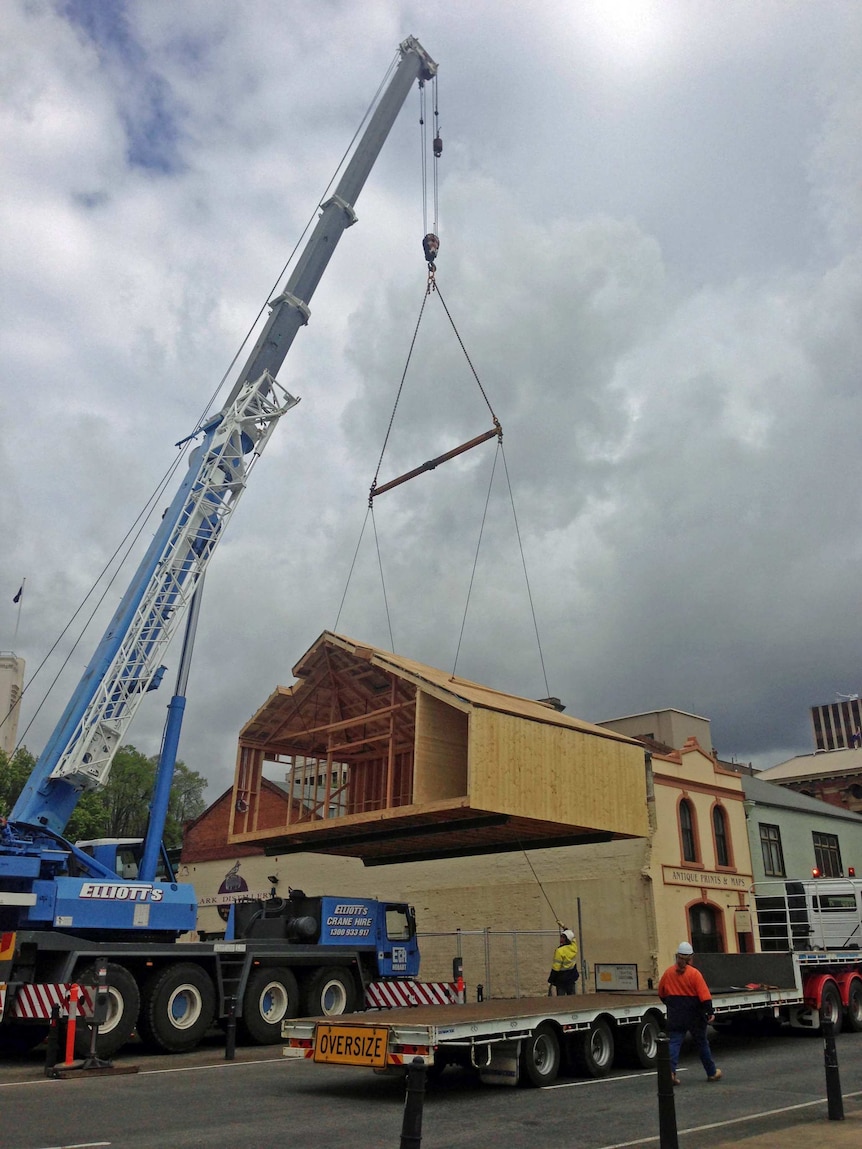 A replica of the Antarctic hut used by explorer Douglas Mawson is lowered into place near Hobart's waterfront.