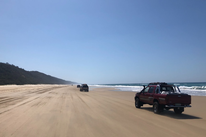 four wheel drives driving along a wide, long stretch of beach