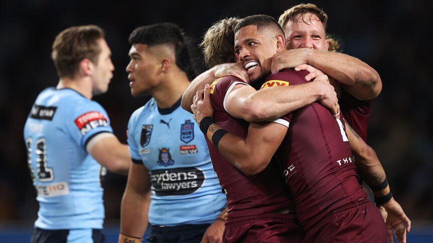 Dane Gagai is hugged by Queensland Maroons teammates after scoring a State of Origin try against the NSW Blues.
