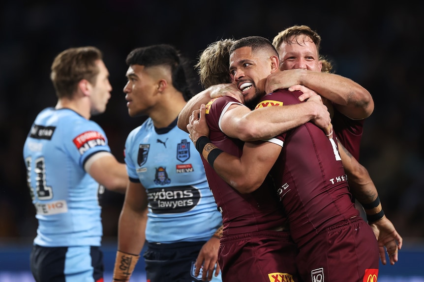 Dane Gagai es abrazado por sus compañeros de equipo de los Queensland Maroons después de marcar un try de State of Origin contra los NSW Blues.