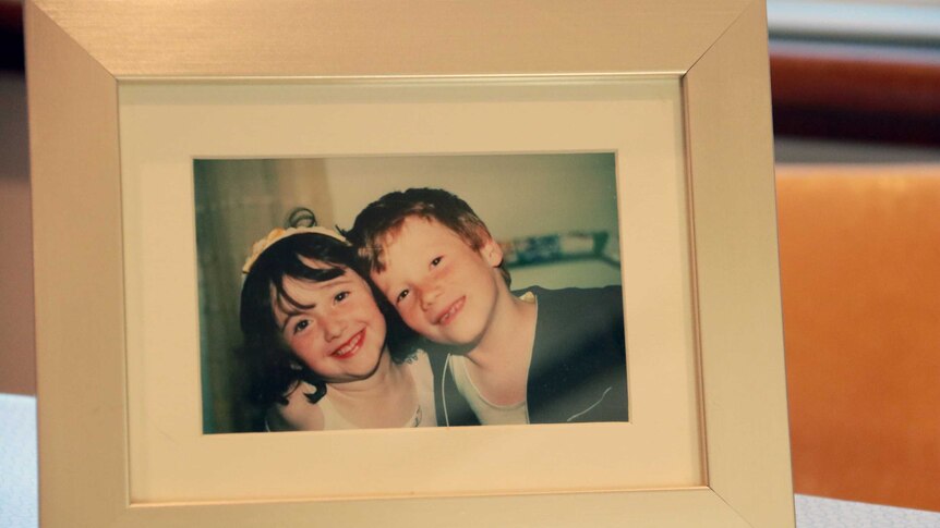 A photograph of a photo frame containing a picture of Beth Wright and her half-brother as children.