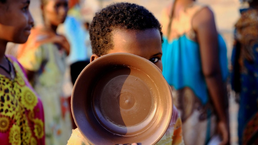 An Ethiopian child who fled war in Tigray region carries his plate as he queues rations