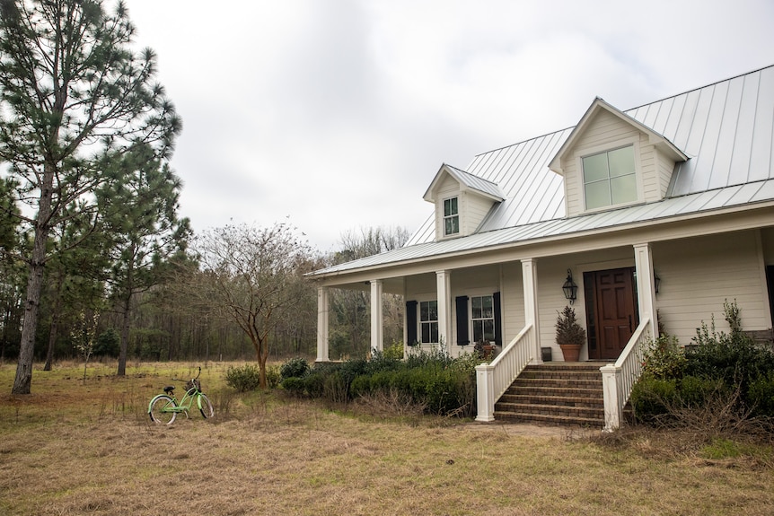 A close up of the front of a two-storey house surrounded by trees.