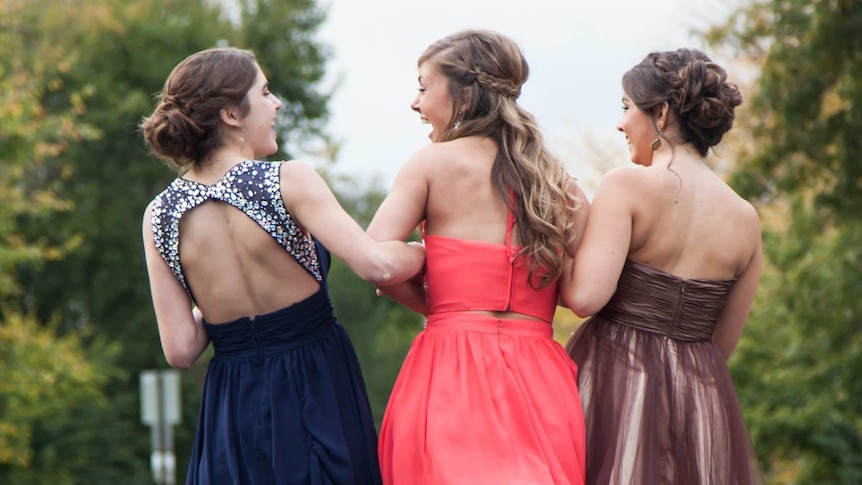 Three young girls in formal dresses laughing