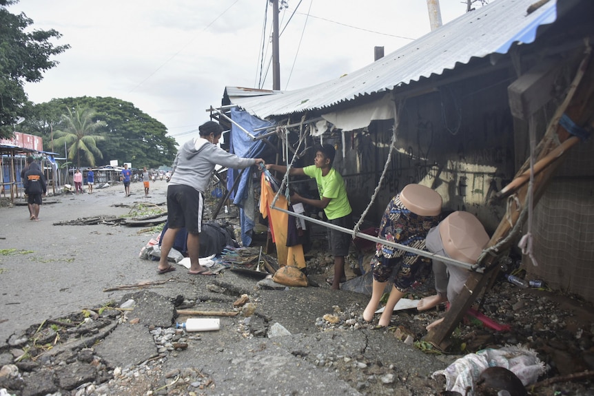 Un homme tente de nettoyer une boutique endommagée à Dili, Timor-Leste