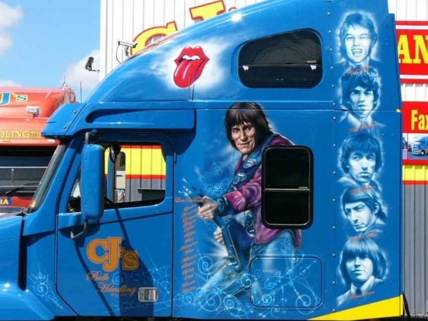 Rolling Stones' Ronnie Wood painted on the side of a blue prime mover closest where the bed is inside