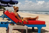 A female tourist wearing a protective face mask sunbathes on a beach in Bali.