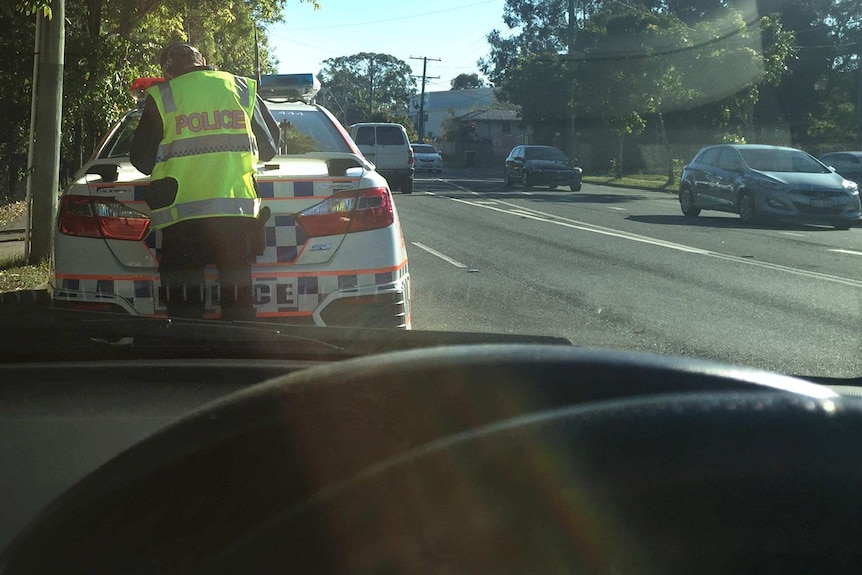 A Queensland police officer pulls over a vehicle for a traffic offence.