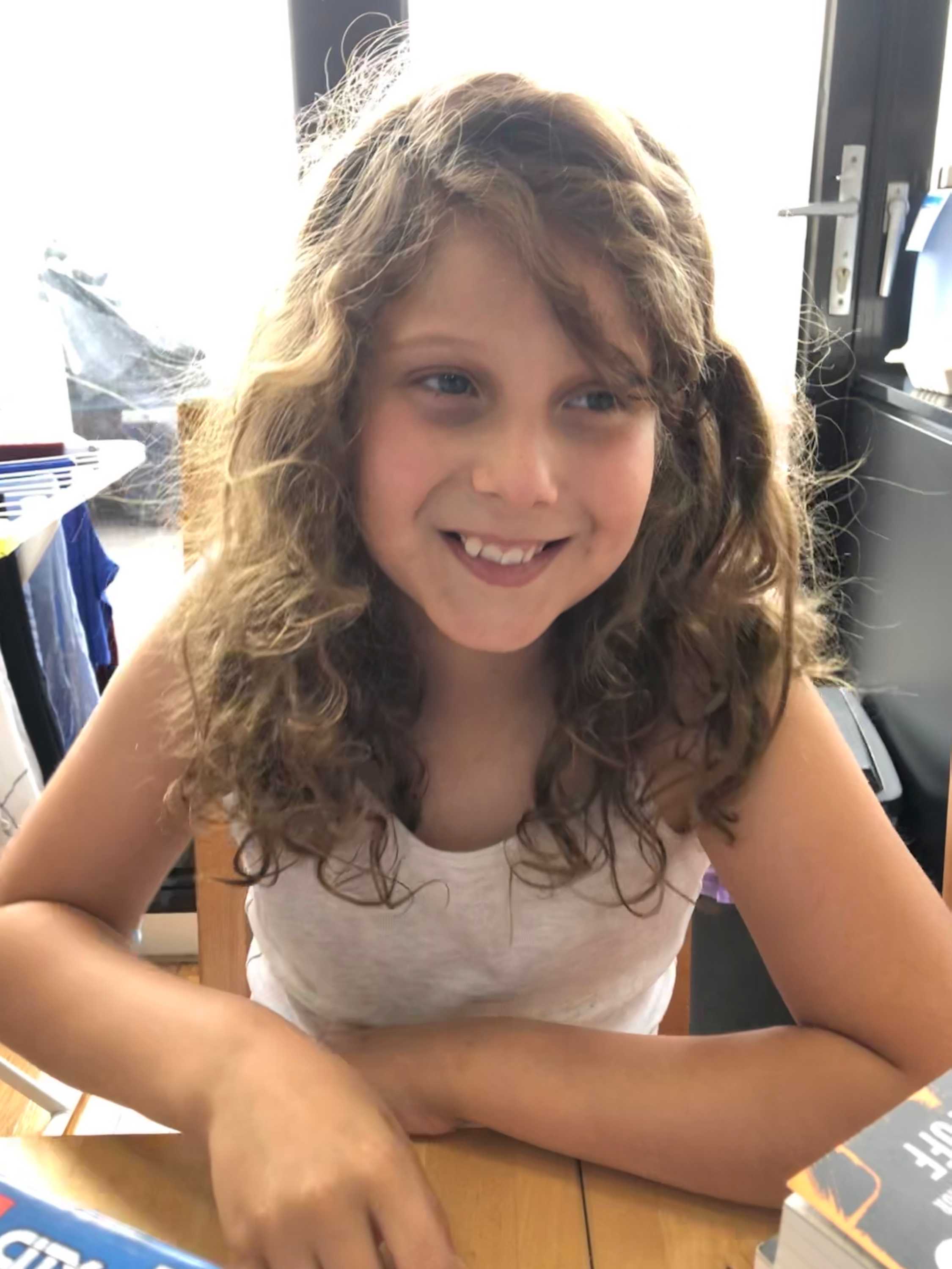 A recent image of Caius, with long curly hair and smiling