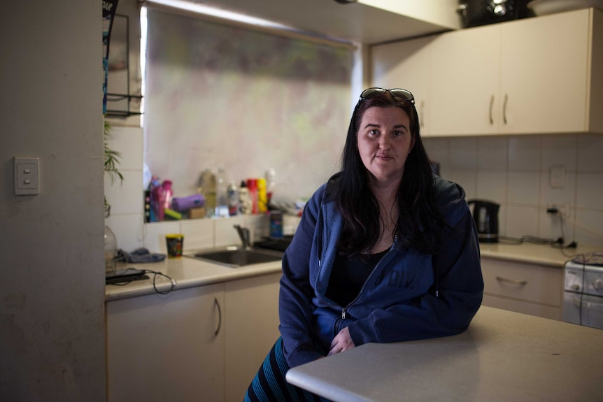 A woman sits in the kitchen of her Kalgoorlie home.