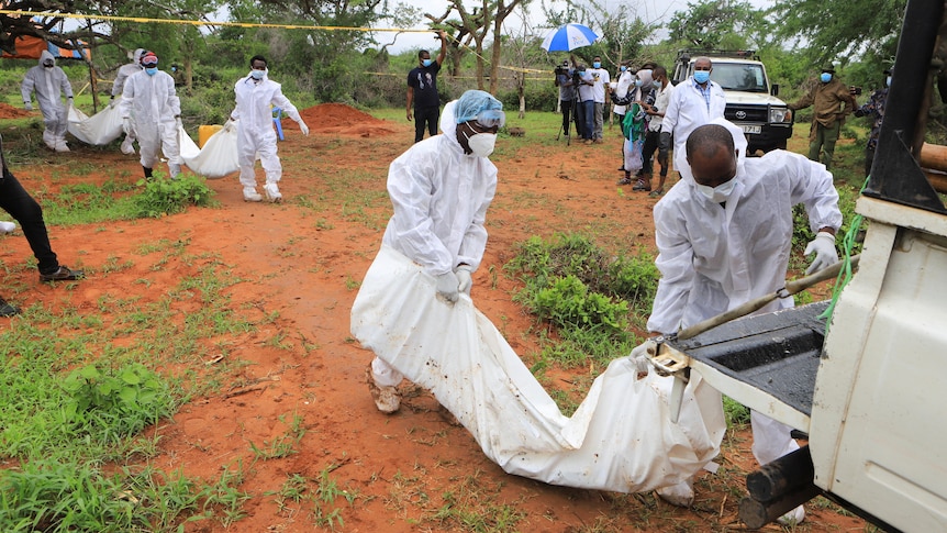 Forensic experts and homicide detectives carry the bodies of suspected members of the cult.