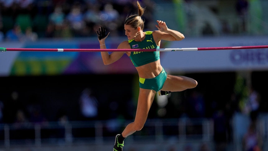 An Australian pole vaulter holds her arms up to make sure she clears the bar during a world championship final.