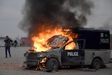 A man films with his mobile phone to a burning police vehicle in Islamabad.