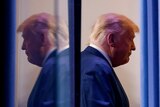 US President Donald Trump reflected in glass wearing a suit