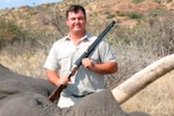 Jewell Crossberg hold a large gun and stands next to a dead elephant.