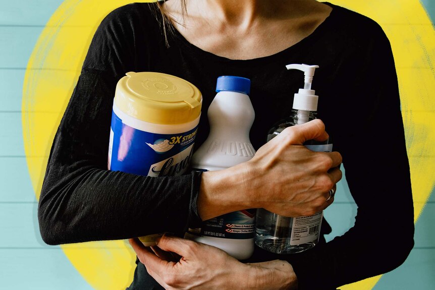 Woman holding three bottles of cleaning products to her chest for a story about spring cleaning your laundry