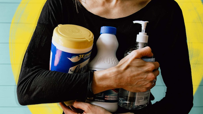 Woman holding three bottles of cleaning products to her chest for a story about spring cleaning your laundry