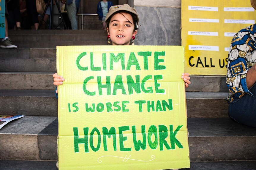 Charlie holds up a sign saying: "Climate change is worse than homework".