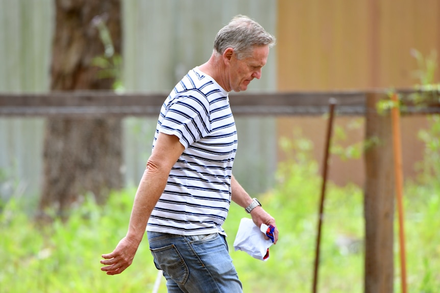 a man carrying a bundle with red threads poking out