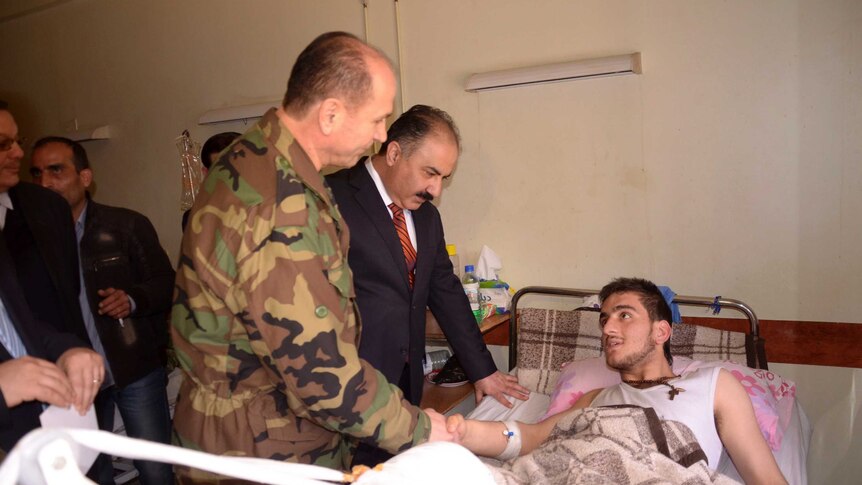 Syrian government officials visit a chemical attack victim