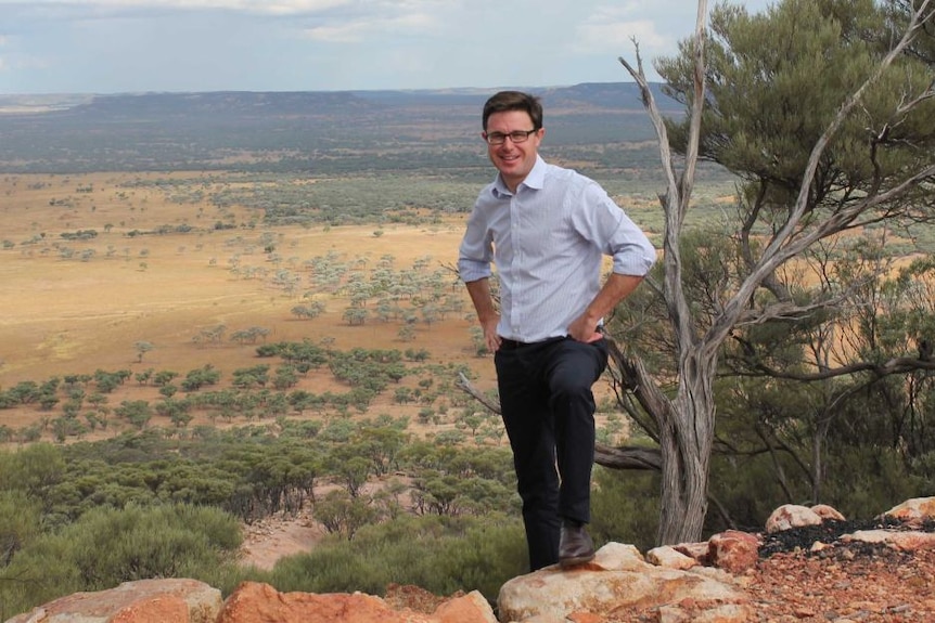 A man in glasses stands up on a bluff overlooking the plains in his electorate