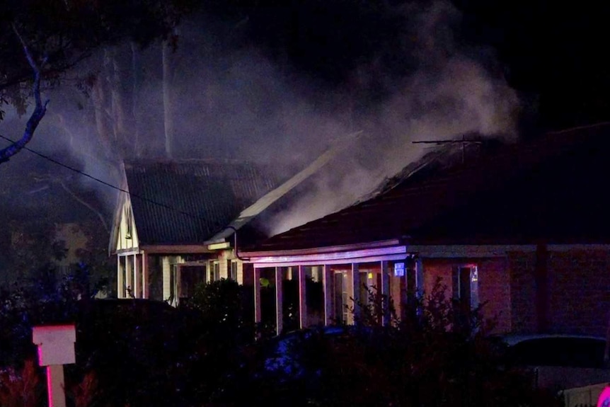A house at night, with smoke emanating from it.