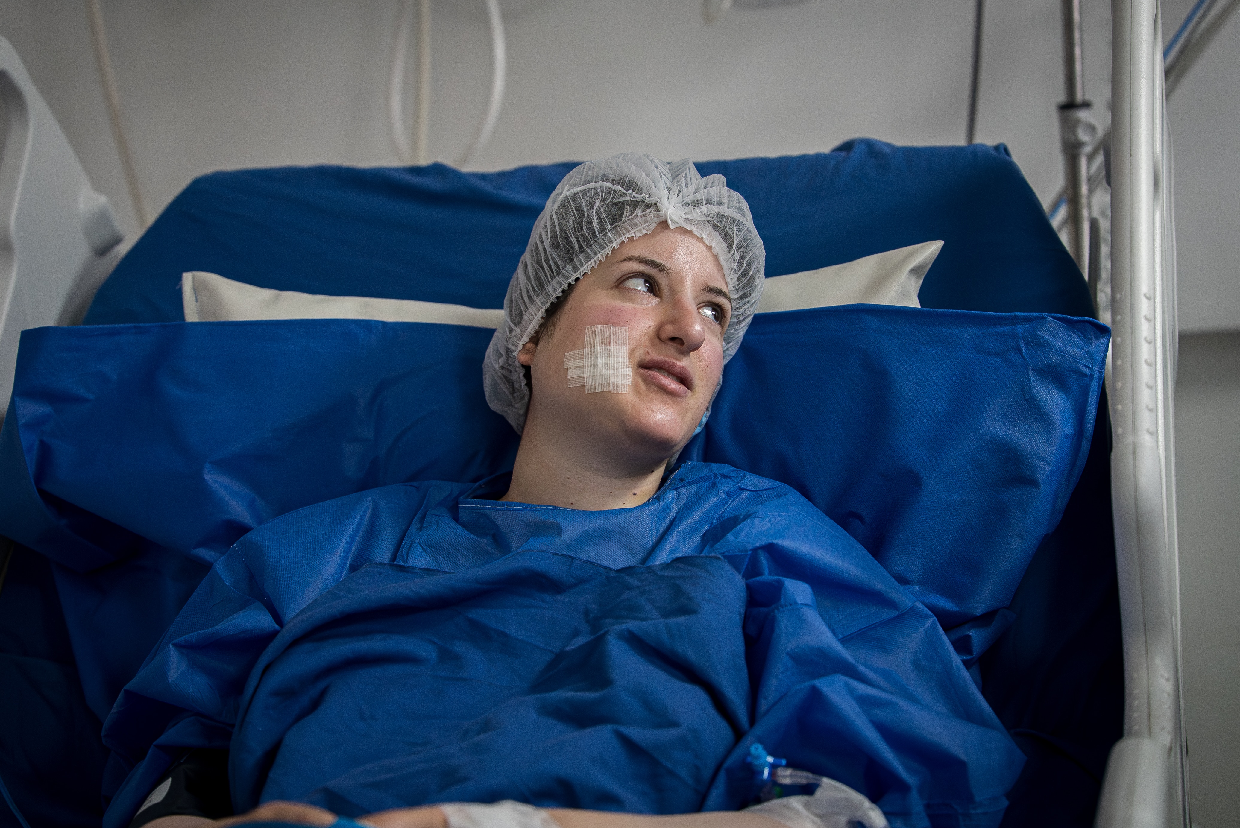 Dania Salameh, wearing a hair net and robe, lies in a hospital bed.