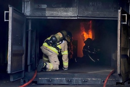 Firefighters sit inside a black box with flames in it