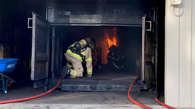Firefighters sit inside a black box with flames in it