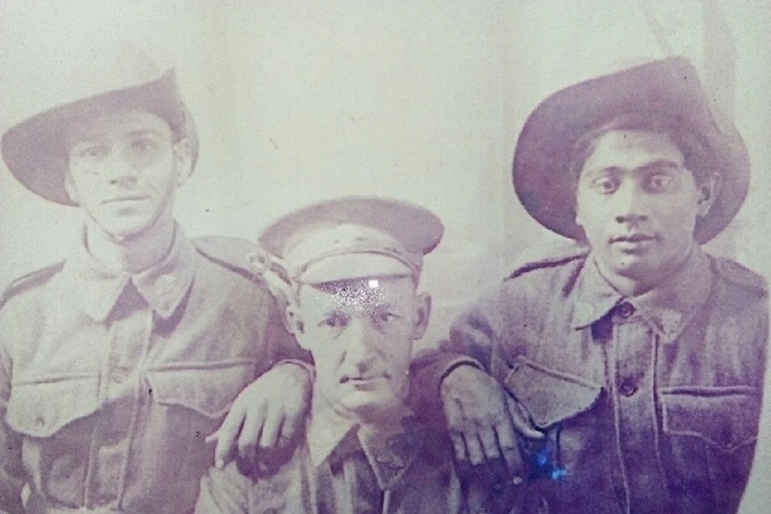 A black and white photo of three men sitting in their Australian Army uniform with digger hats.
