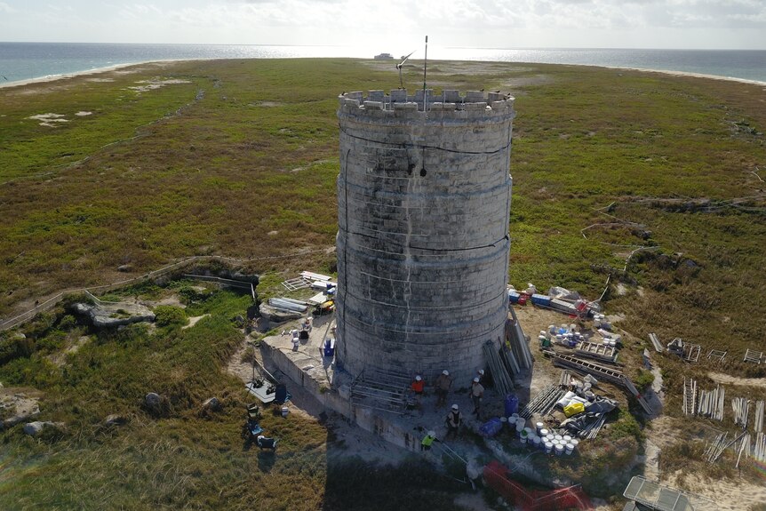 A stone tower on a small island with scaffolding around it