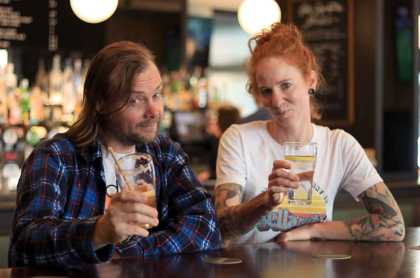 Man and women raise their glasses in a pub, smiling at the camera