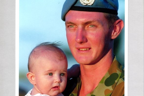 Rodney Hargrave in army uniform and UN beret holds his baby daughter, father and child with the same blue eyes.