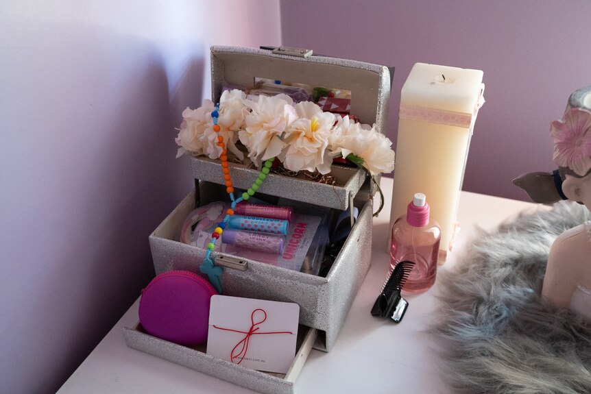 Items in a girl's bedroom including a candle and some flowers.